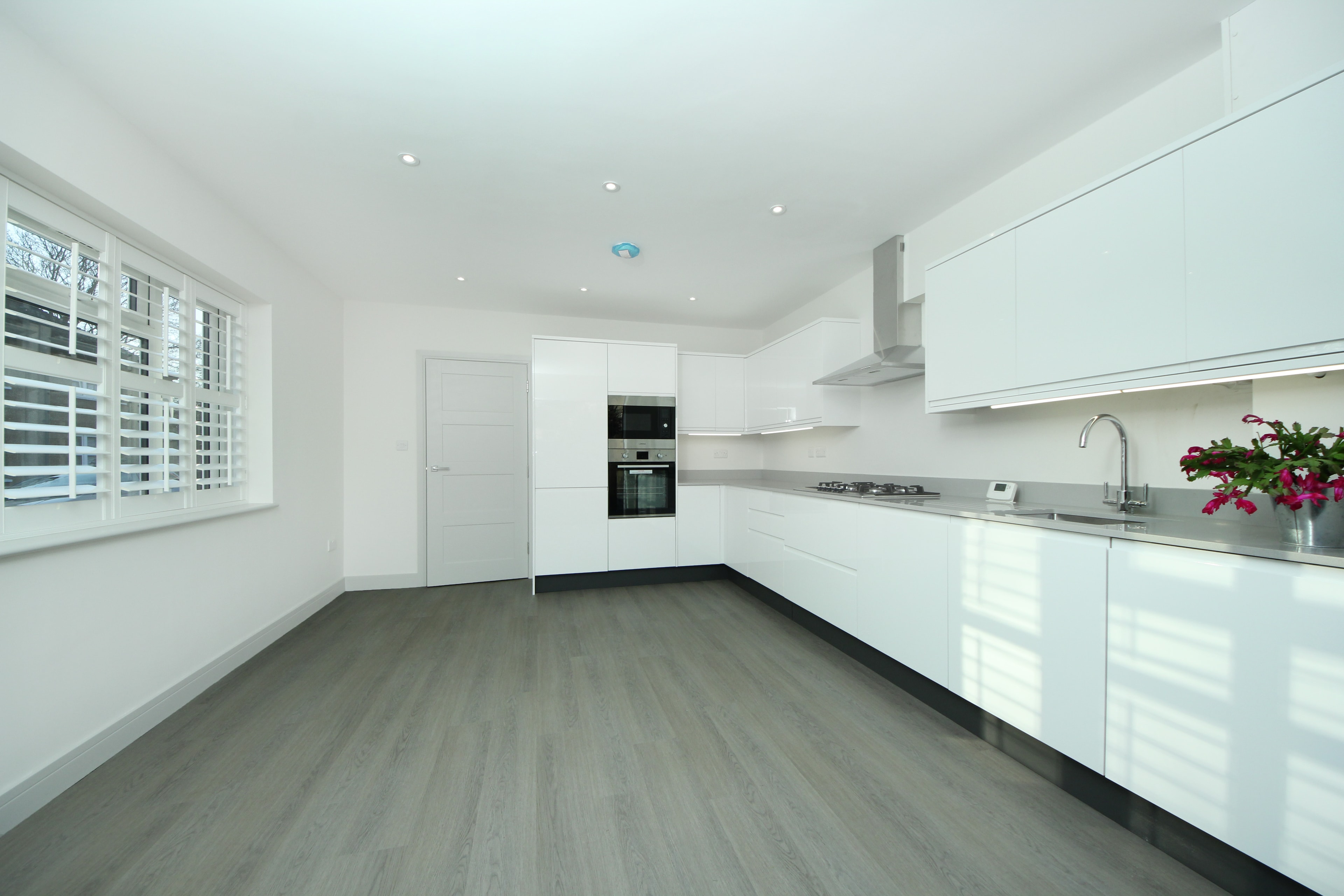 Chilton Avenue — new open-plan kitchen with white gloss units, integrated appliances and grey wood-effect flooring