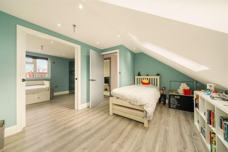 Loft conversion bedroom with teal walls and skylights