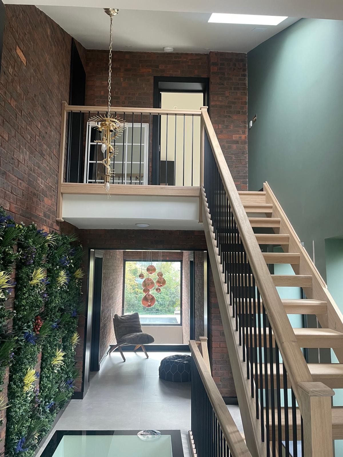 Galley Lane — double-height entrance hall with oak and steel open staircase, living wall, glass floor void and copper cluster pendant lighting