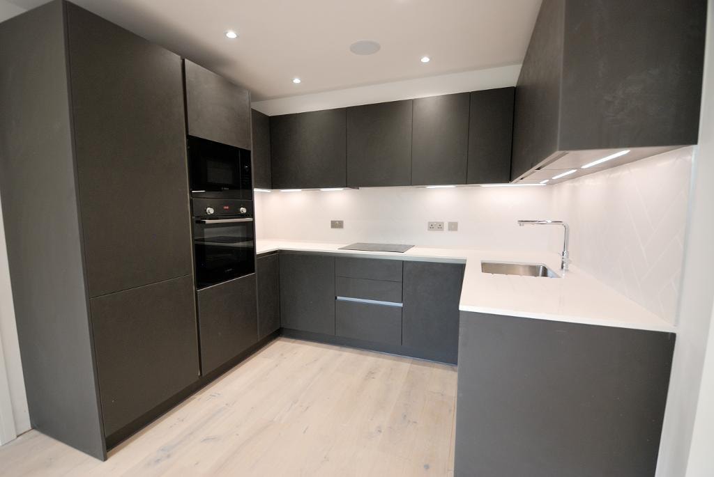 Golden Manor — luxury kitchen with dark matt cabinetry, white worktops and oak flooring