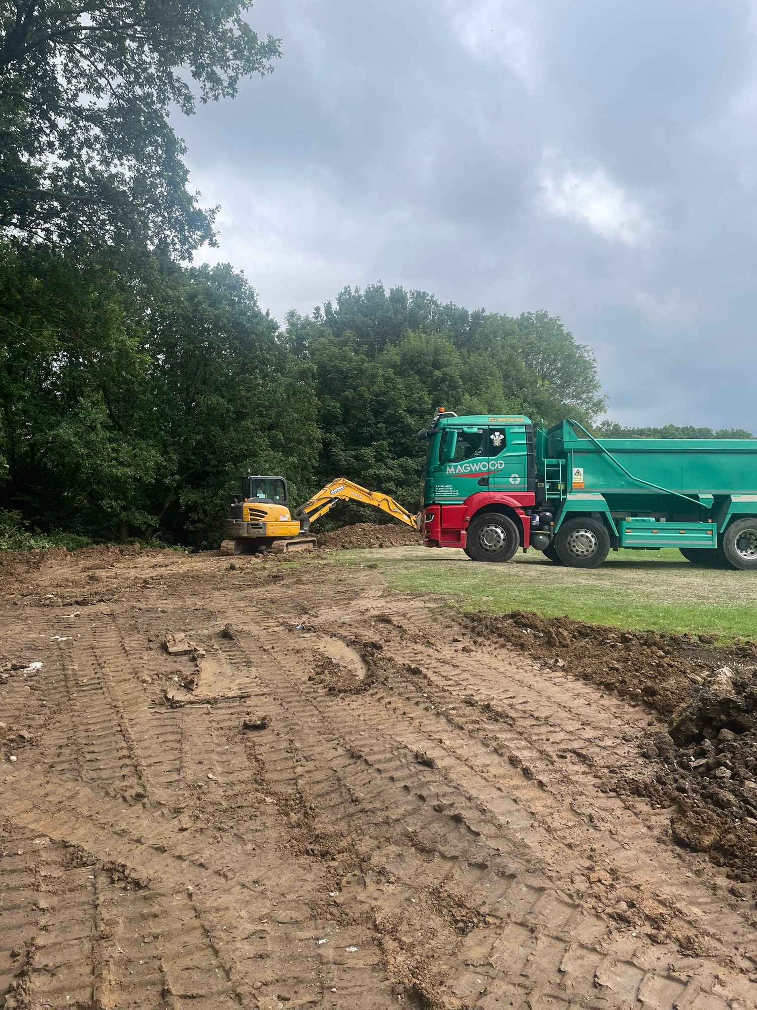 Excavator loading soil into dump truck during groundworks