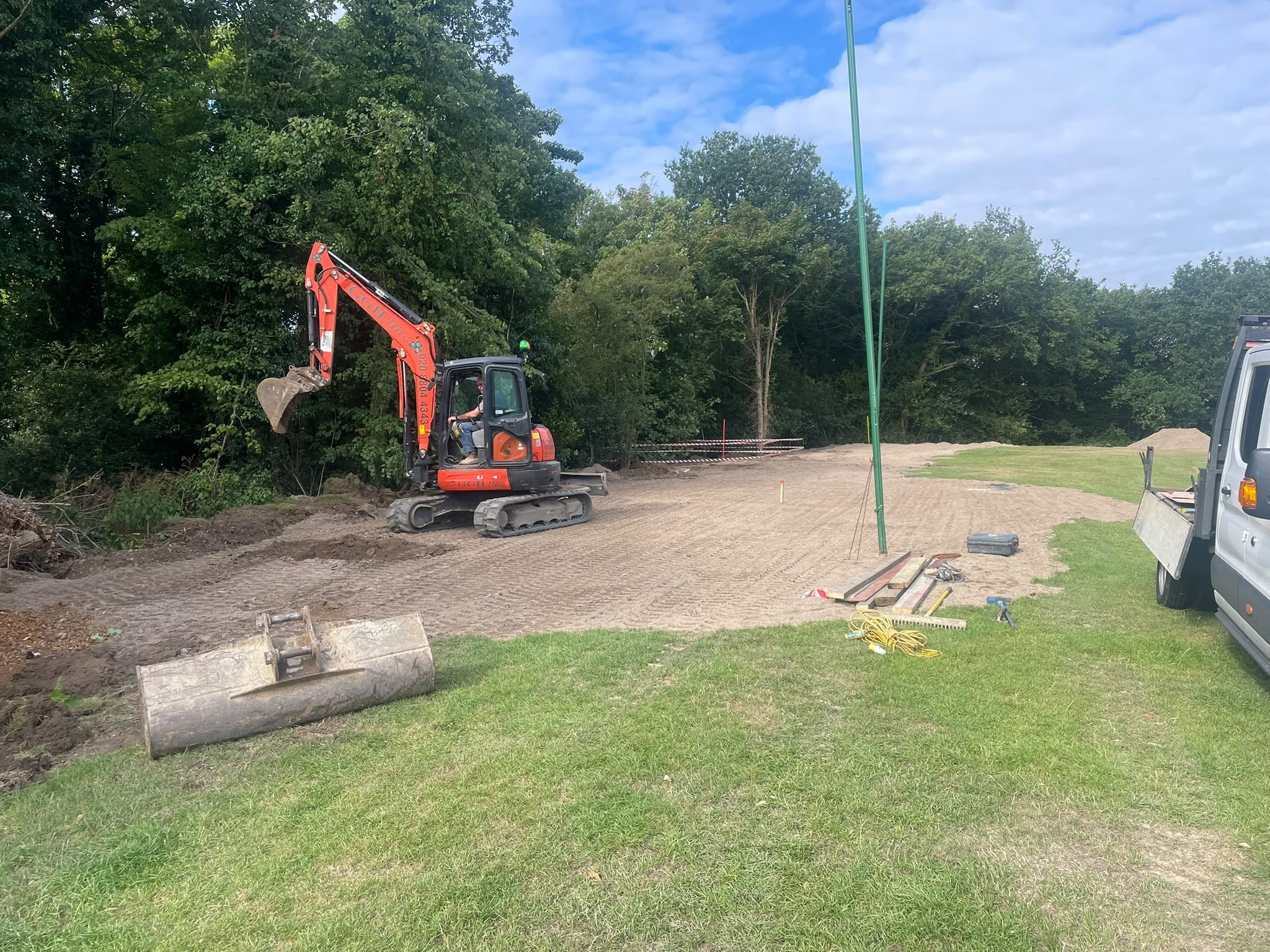 Red excavator clearing land on construction site