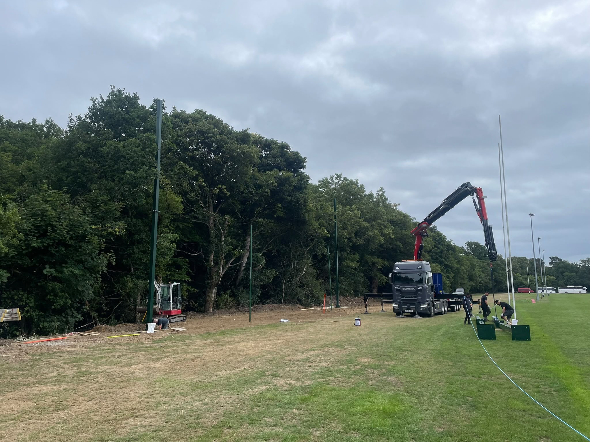 Crane erecting net support poles alongside rugby posts