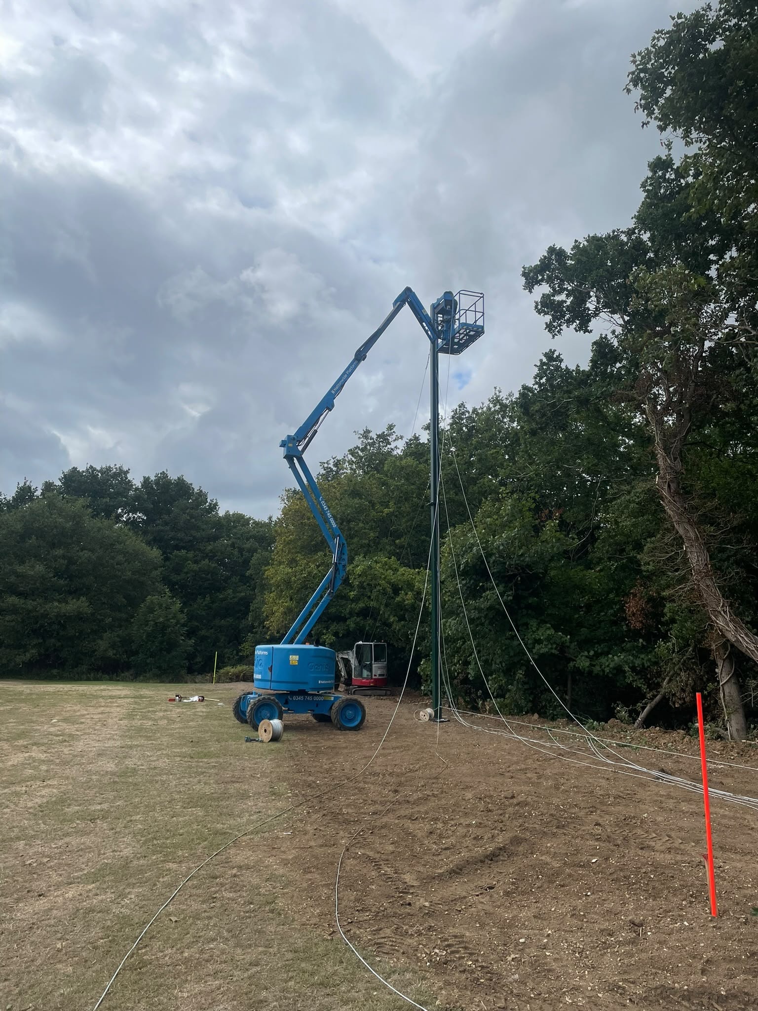Blue boom lift reaching tall net poles during installation