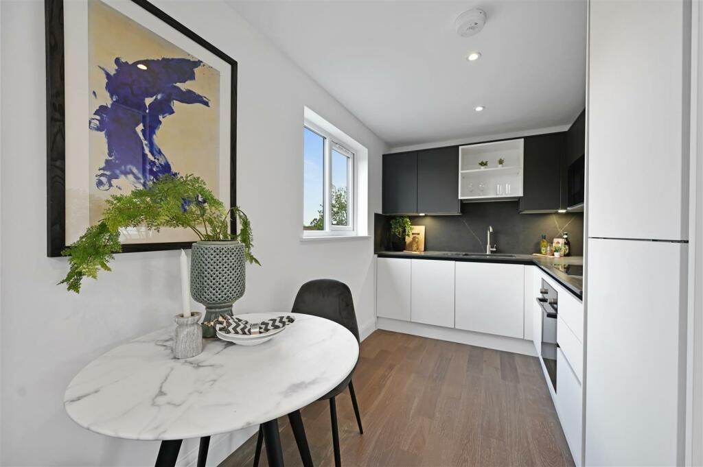 Kitchen and dining area with dark cabinetry, marble table and artwork