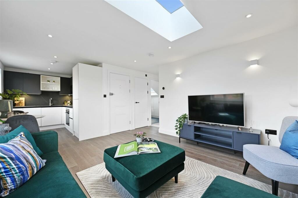 Living room with green sofa, TV unit and rooflight