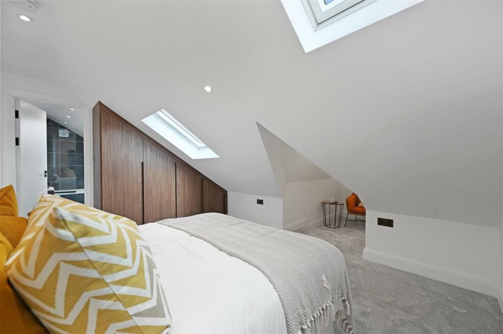 Loft bedroom with twin skylights, walnut wardrobes and en-suite beyond