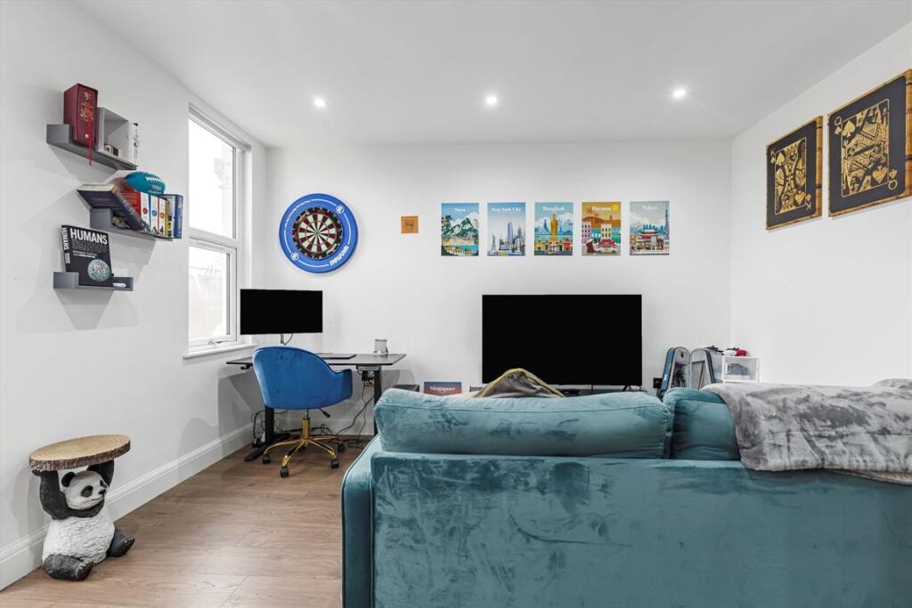 Melbourne Avenue — studio living room with teal velvet sofa, dartboard, travel posters and home office setup