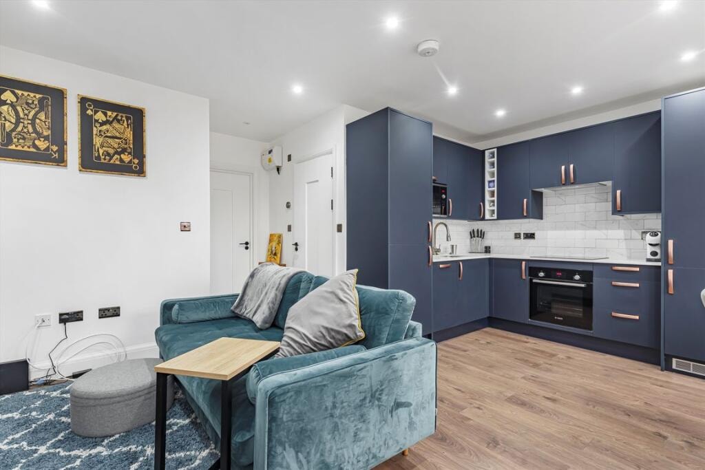 Melbourne Avenue — studio flat open-plan living and kitchen with teal sofa and navy kitchen with copper handles