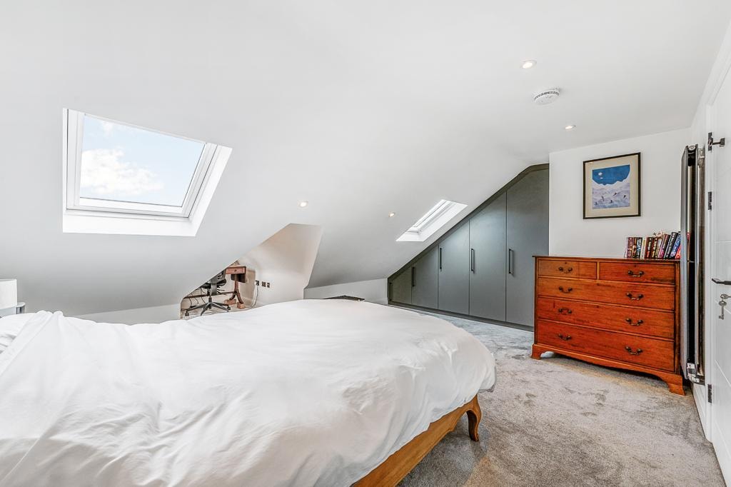 Melbourne Avenue — loft bedroom with two Velux skylights, bespoke grey fitted wardrobes within sloped ceiling and period chest of drawers