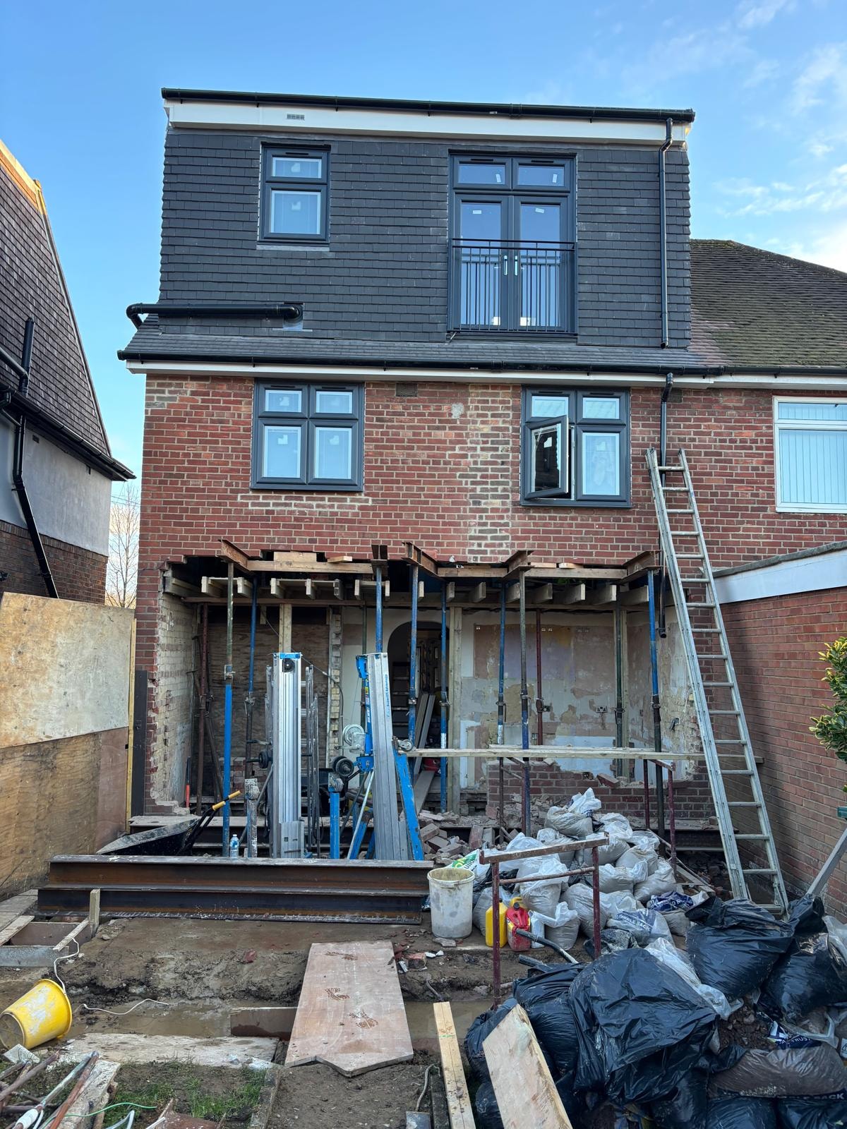 Pursley Road — rear elevation mid-build showing completed loft dormer with dark cladding and steel frame for rear extension
