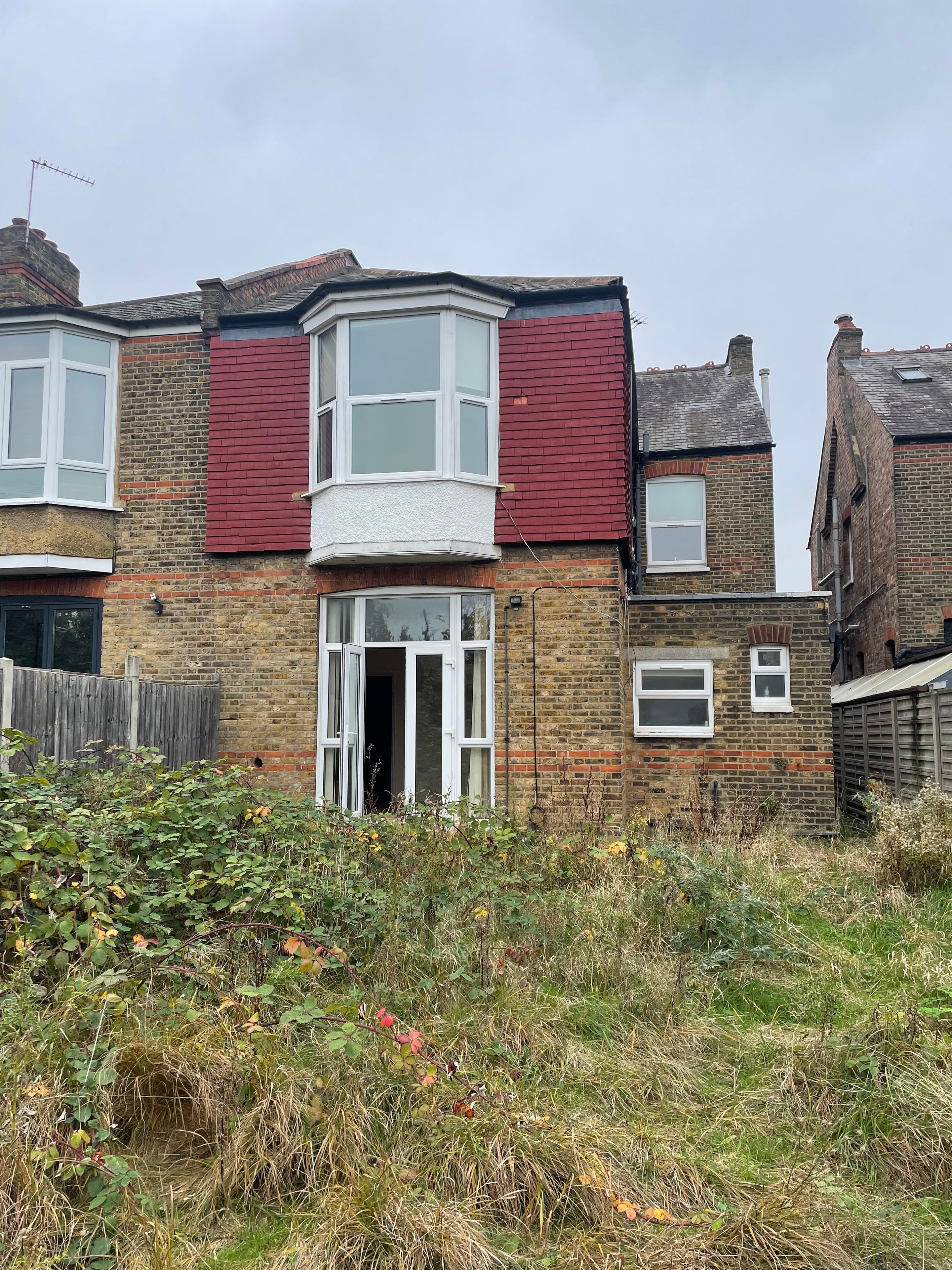 Original rear of the house before works — red corrugated roof and overgrown garden