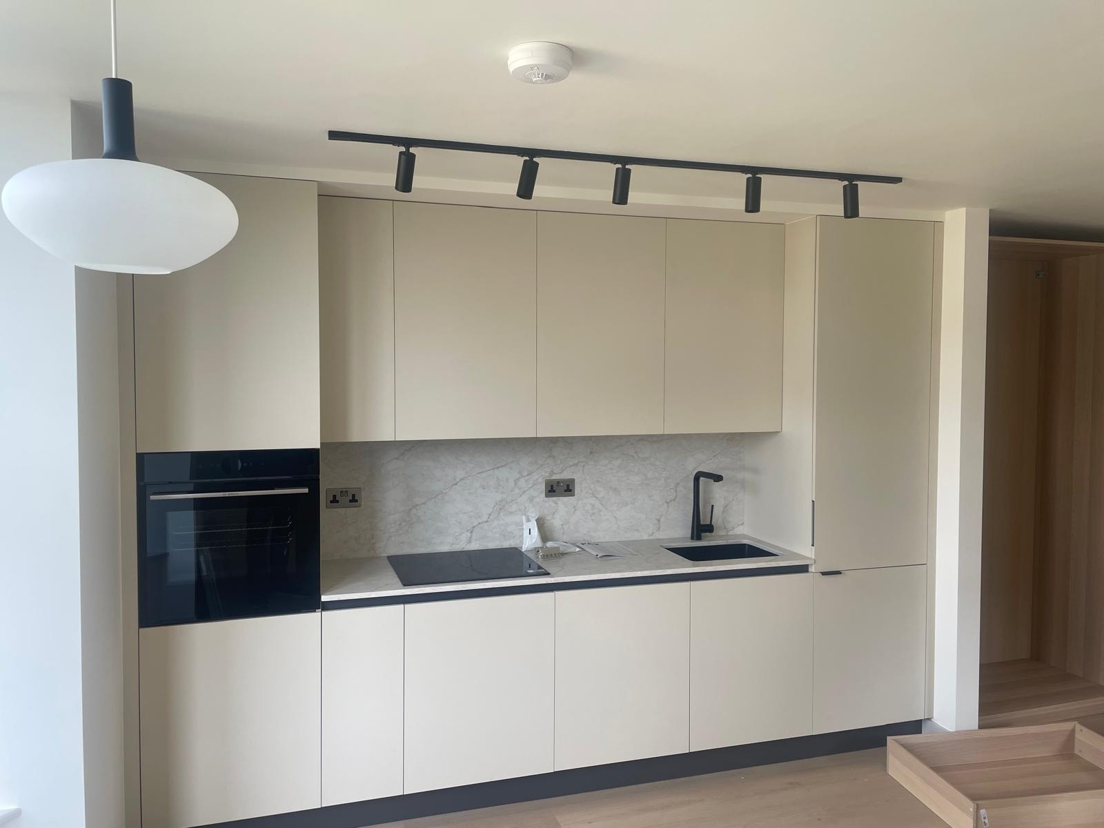 Flat interior — cream handleless kitchen with marble splashback and track lighting