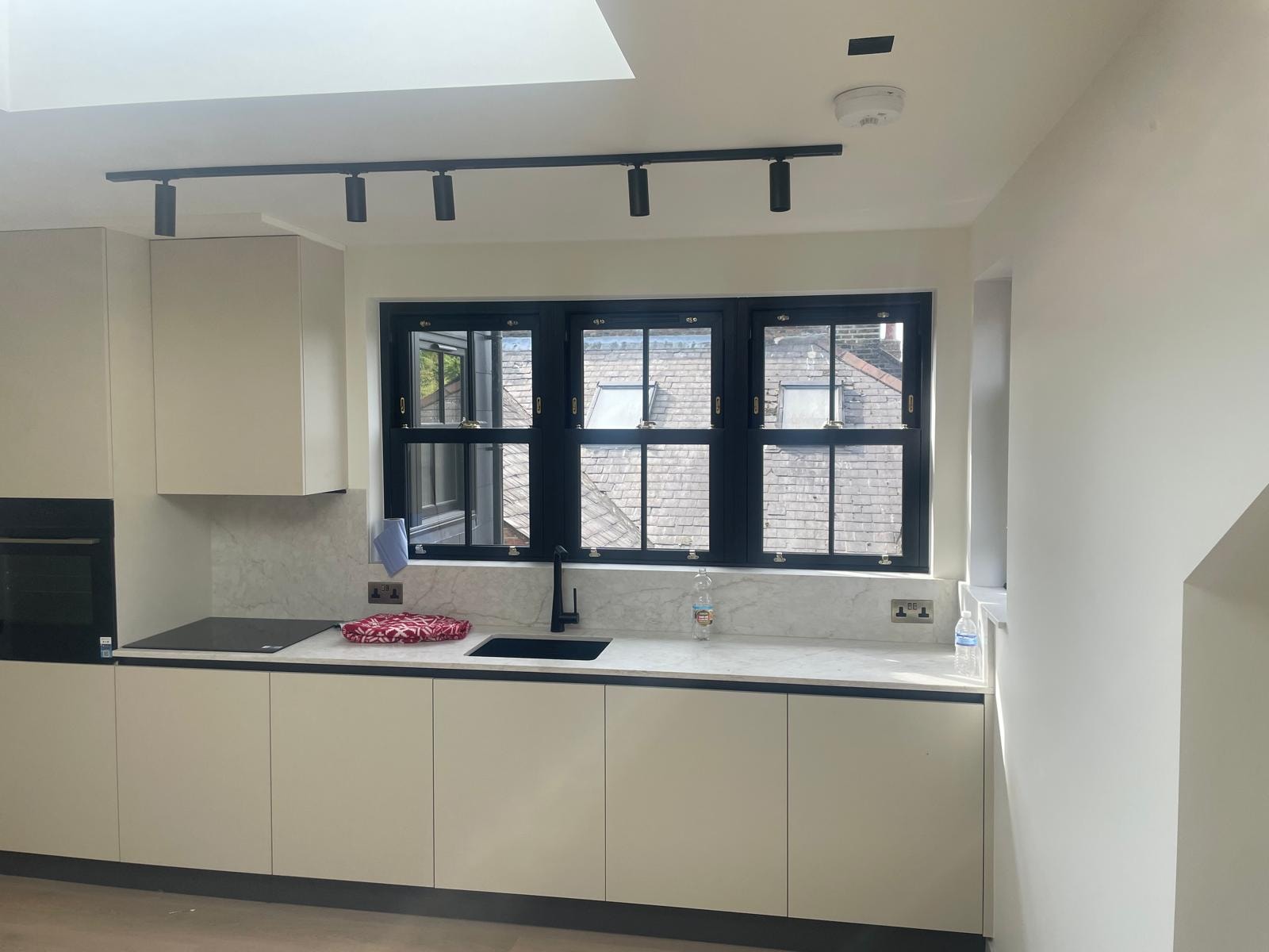 Kitchen with black-framed sash windows, marble worktop and track lighting