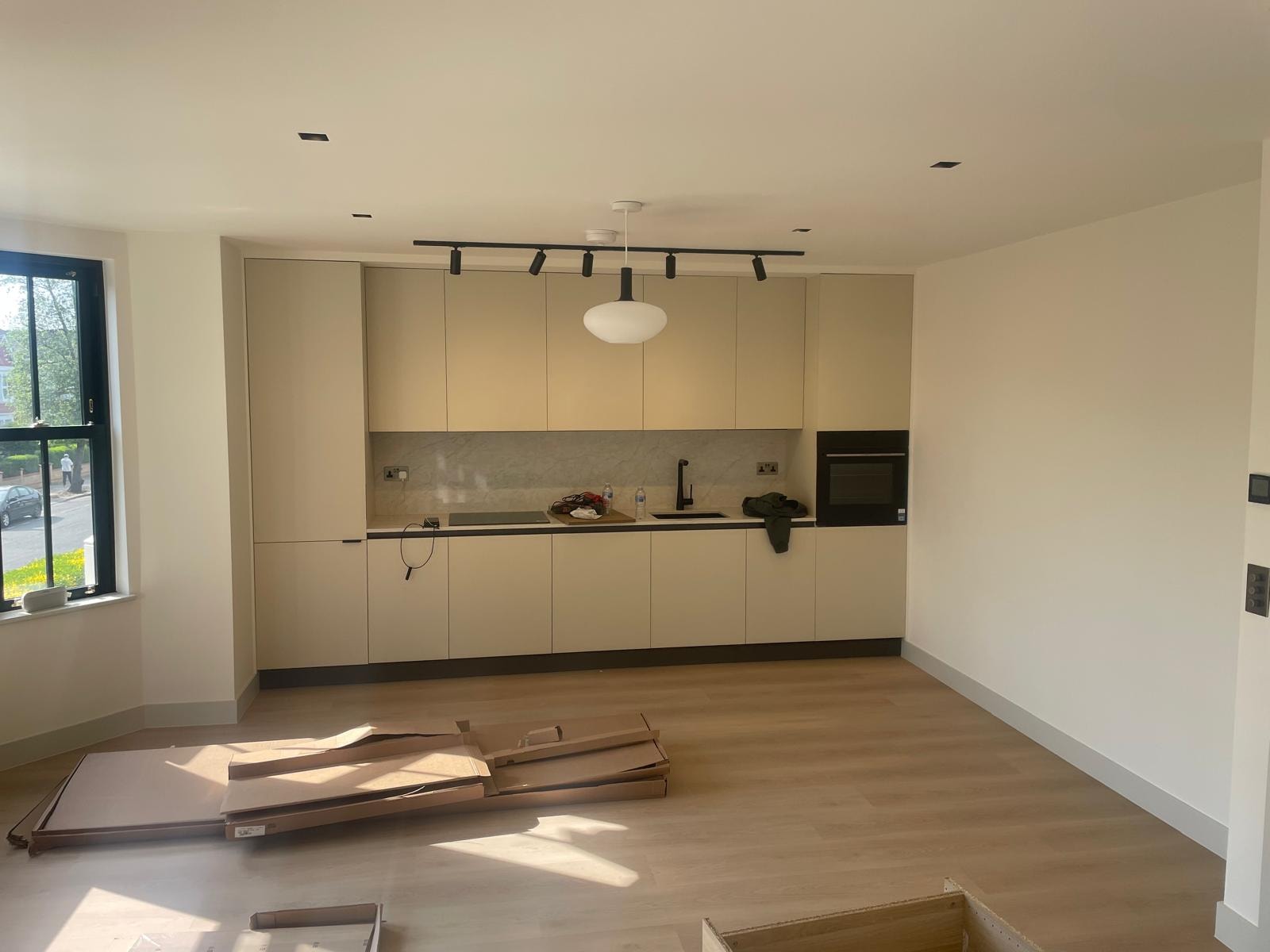 Open-plan kitchen and living space with cream units and oak flooring
