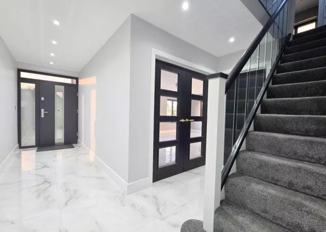 3 Warburton Close — entrance hall with marble-effect flooring, black-framed glazed internal doors and glass balustrade staircase