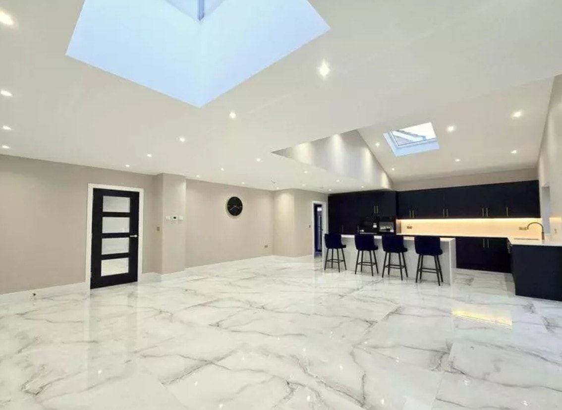 3 Warburton Close — open-plan kitchen and living space in the rear extension with large skylights, marble-effect floor and navy kitchen