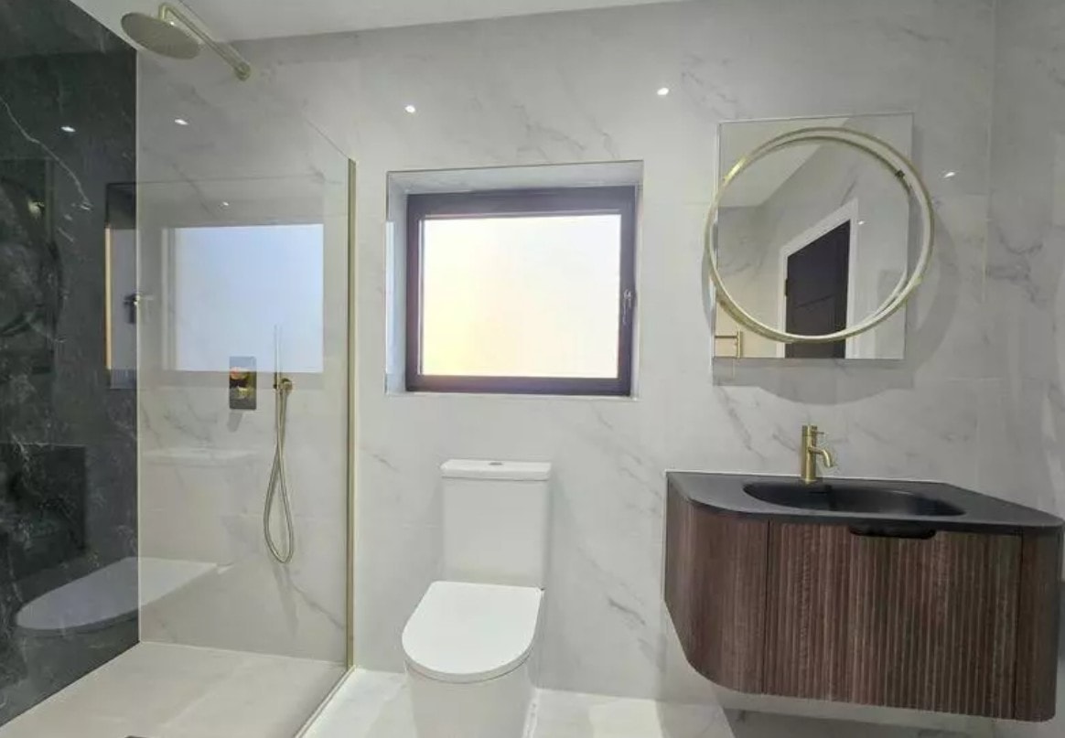 3 Warburton Close — bespoke navy kitchen with brass handles, white quartz island and bifold doors to garden