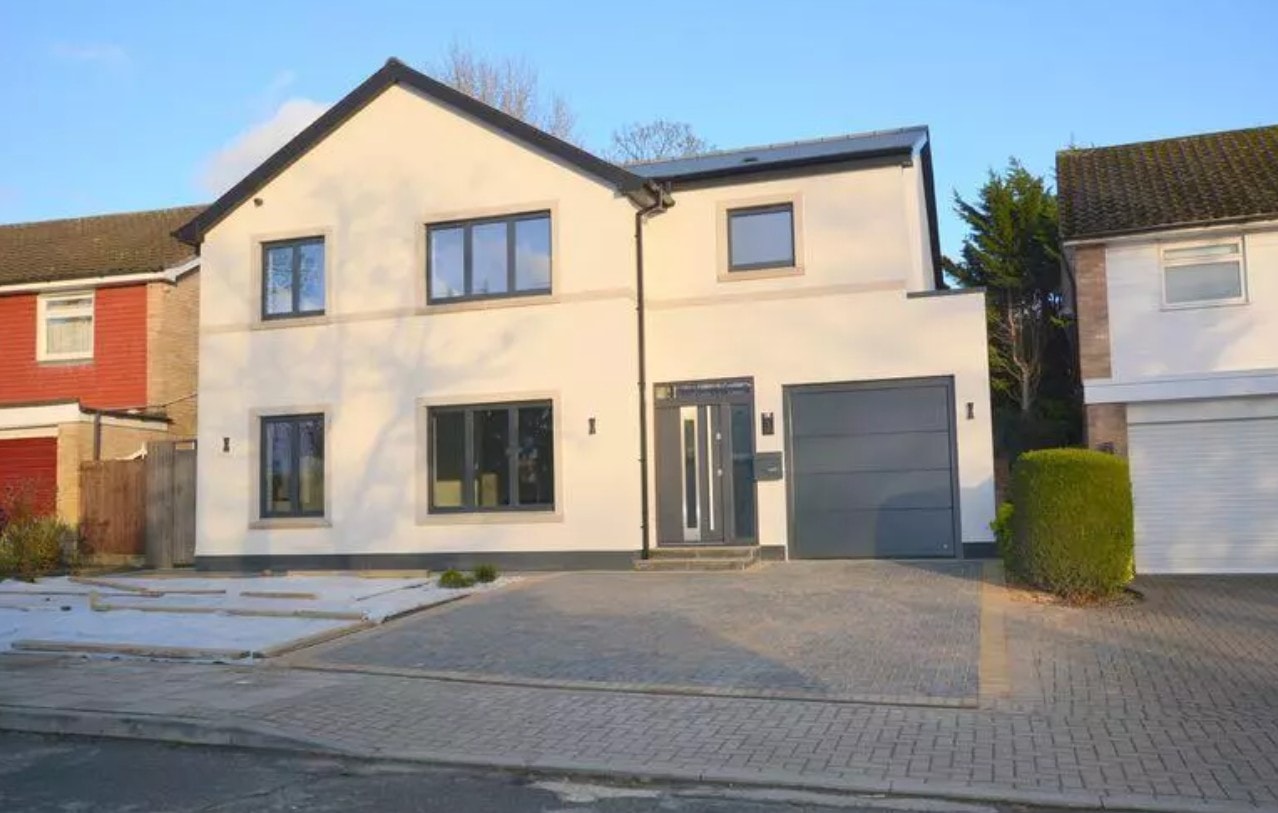3 Warburton Close — completed rear elevation at dusk showing single-storey extension with vaulted roof, bifold doors and landscaped patio