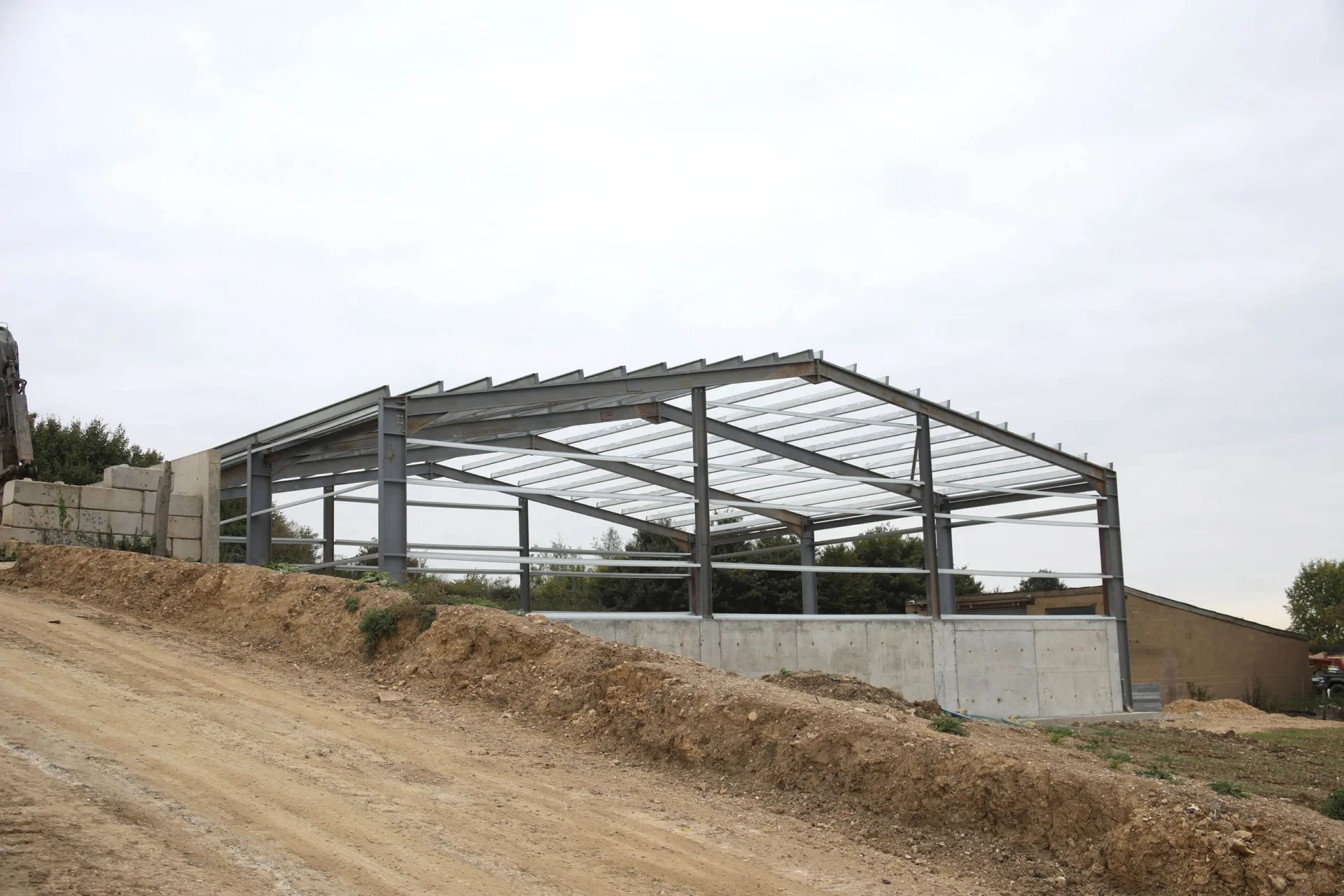 Widdington Recycling — new warehouse steel portal frame under construction on concrete retaining wall base