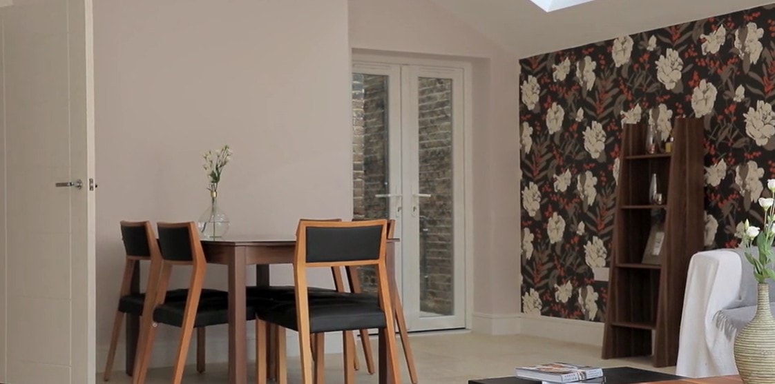 Dining area with floral wallpaper accent wall and French doors