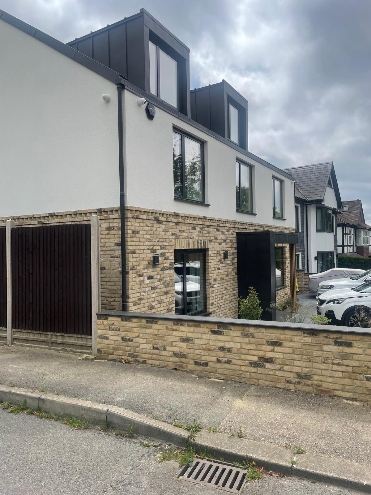 Bellfield Avenue — completed side elevation showing brick base, white render upper floors and dark zinc loft dormers