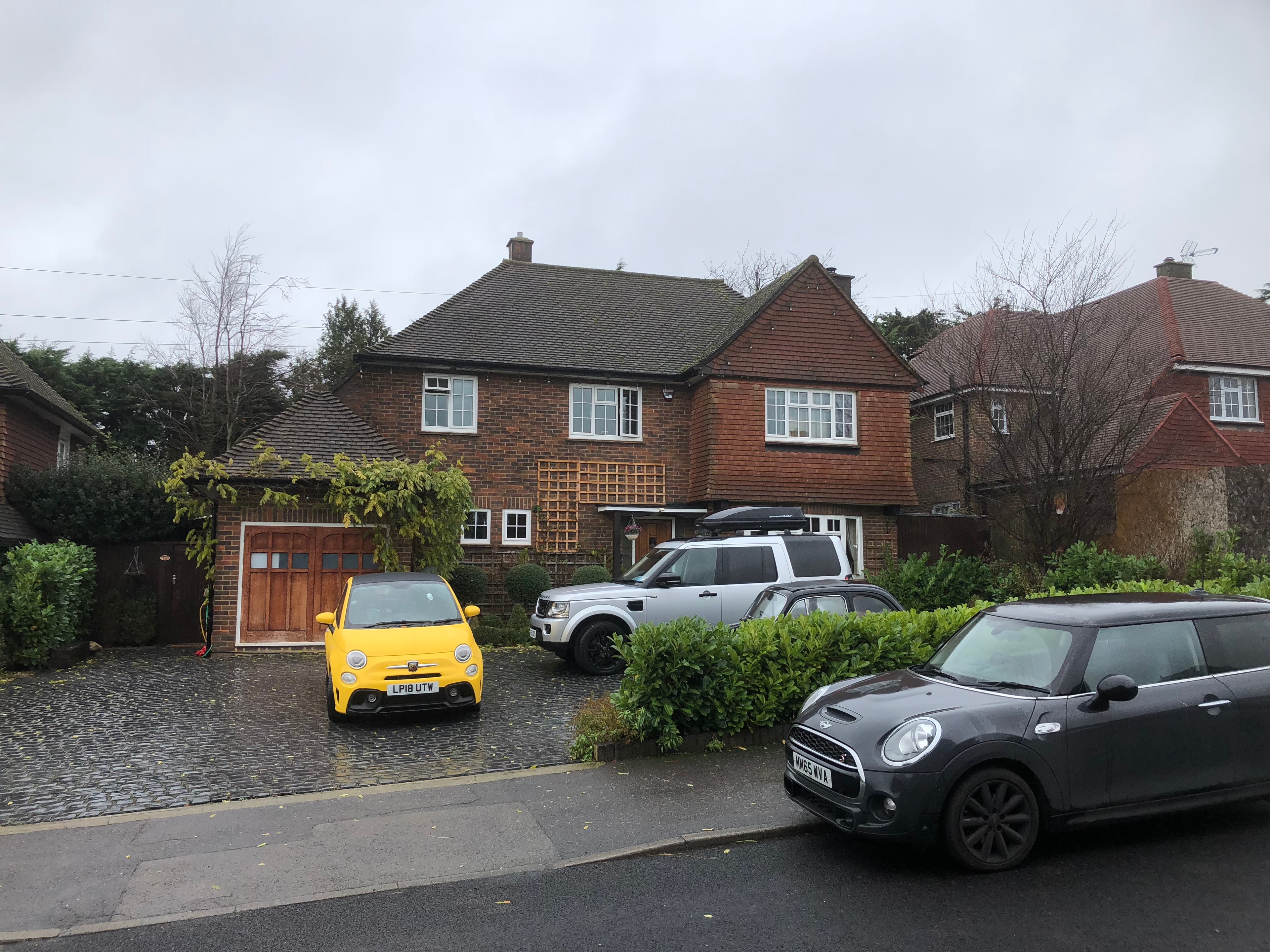 The Comyns — original front elevation with parked cars and driveway